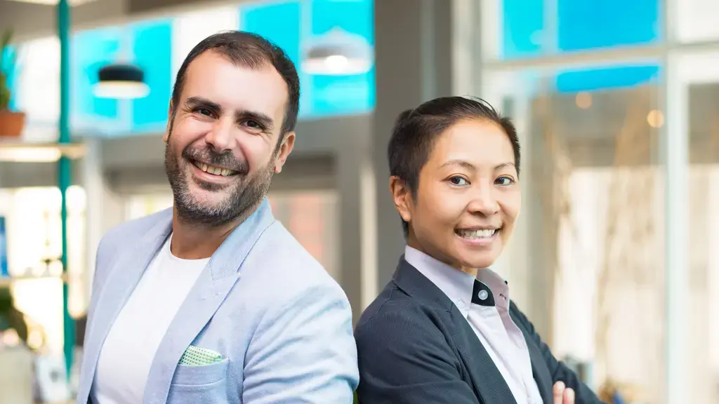 Liderança Asiática x Liderança Americana Mulher asiática gestora de empresa. Homem americano alta liderança. Ambos sorriem - representando que possível hamonia entre liderança asiática e liderança americana.